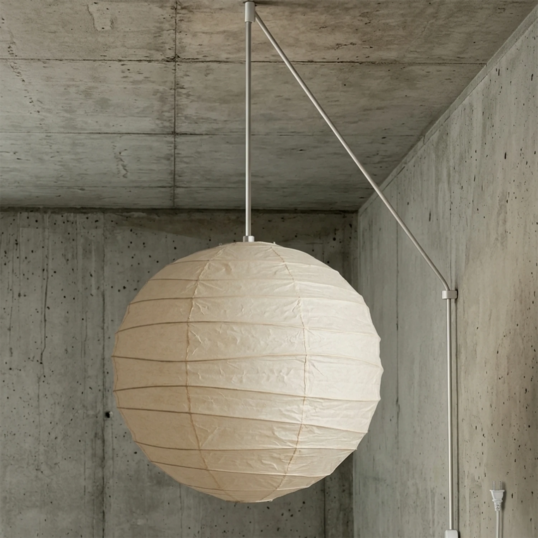 Paper globe pendant on a white swag cord mounted against a concrete wall