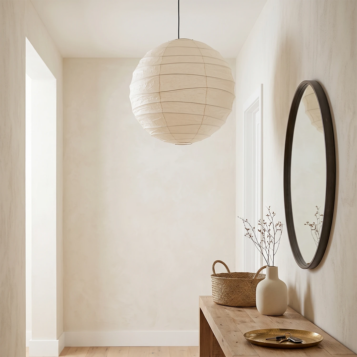 Paper pendant beside a round mirror against a warm plaster wall
