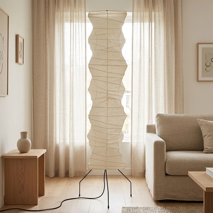 Rice paper floor lamp by a curtained window next to a grey armchair
