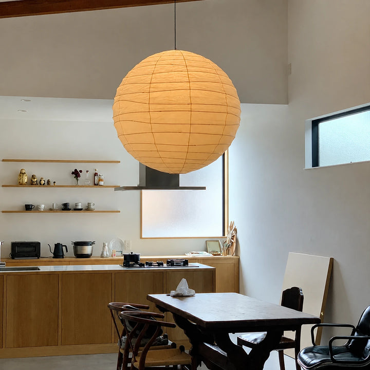 Rice paper globe pendant glowing warm above a modern kitchen dining table