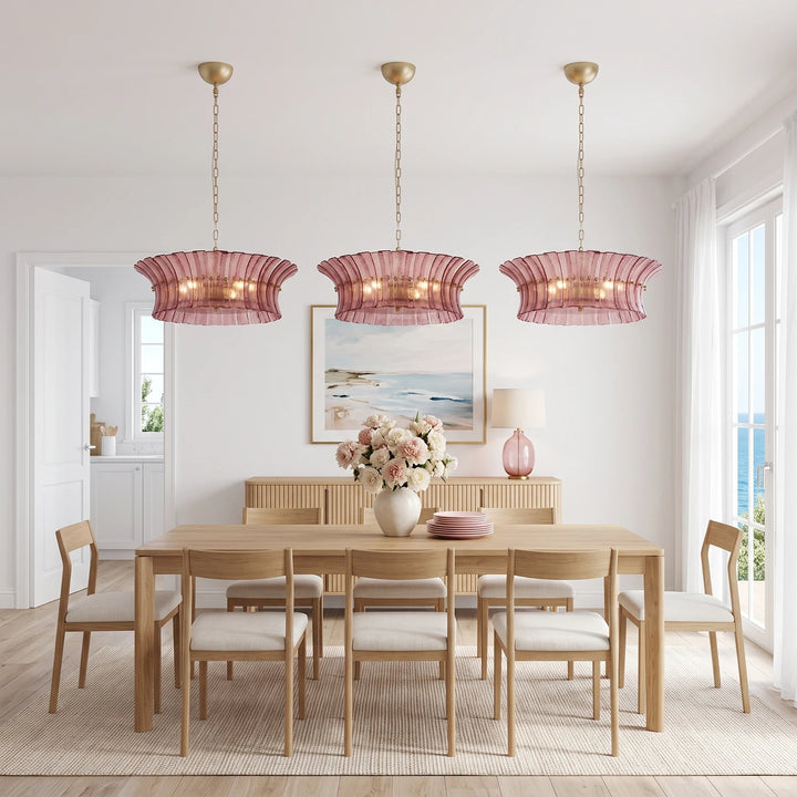 Three rose glass pendants above a light oak table in a seaside dining room