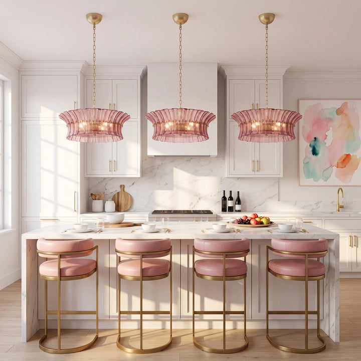 Three rose glass pendants above a pink kitchen island with matching stools