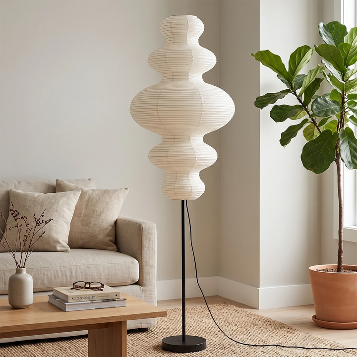 Sculptural paper floor lamp beside a corner bookshelf and armchair