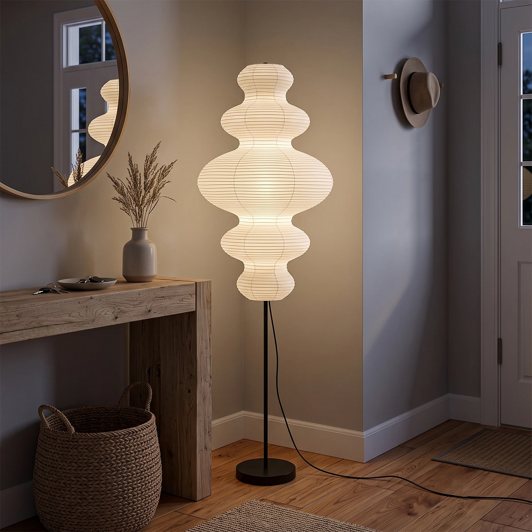 Sculptural paper floor lamp in an entryway beside a round mirror and console