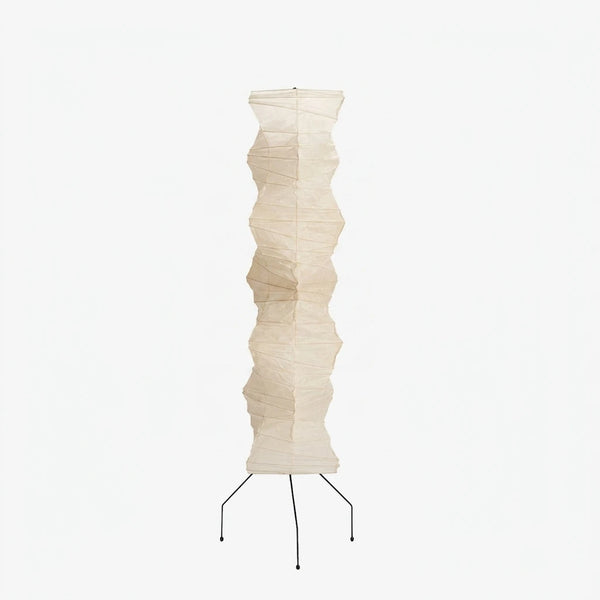 Tall sculptural paper floor lamp with black tripod base on a soft grey background