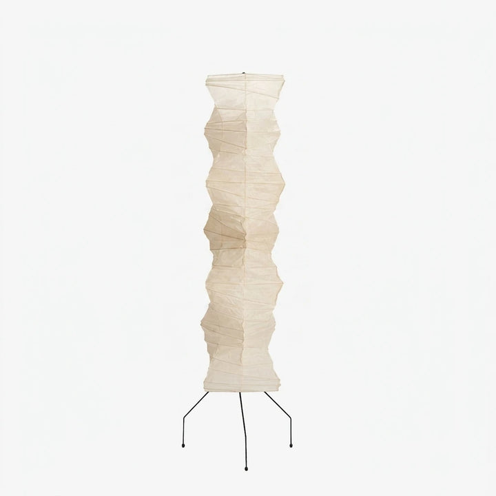 Tall sculptural paper floor lamp with black tripod base on a soft grey background