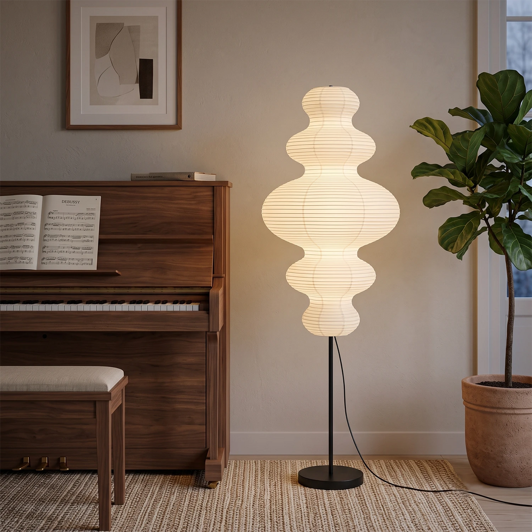 Sculptural paper floor lamp beside an upright piano in a cozy corner