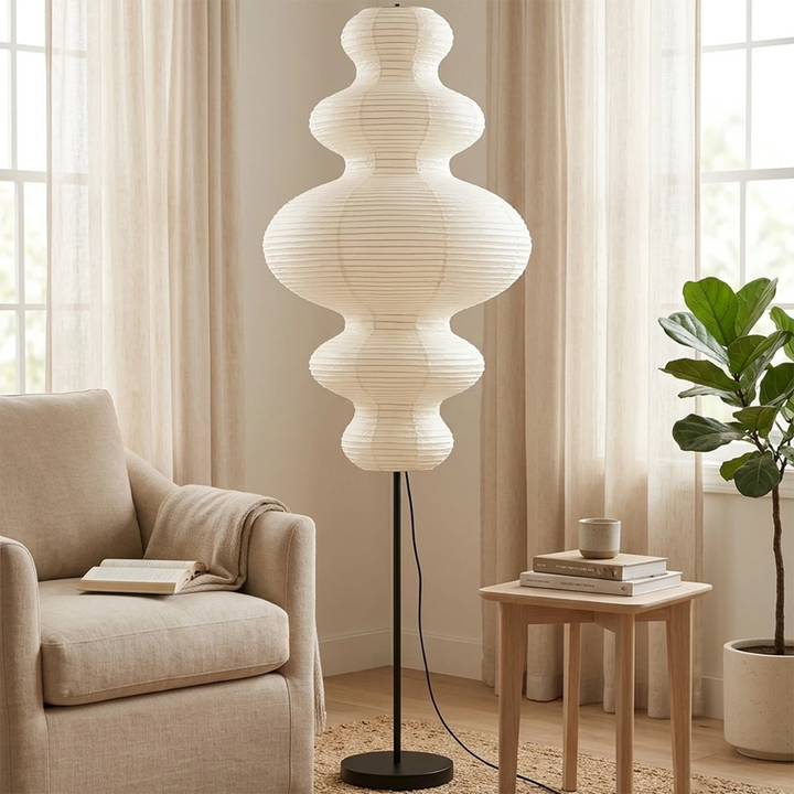 Sculptural paper floor lamp beside tall windows in a bright lounge
