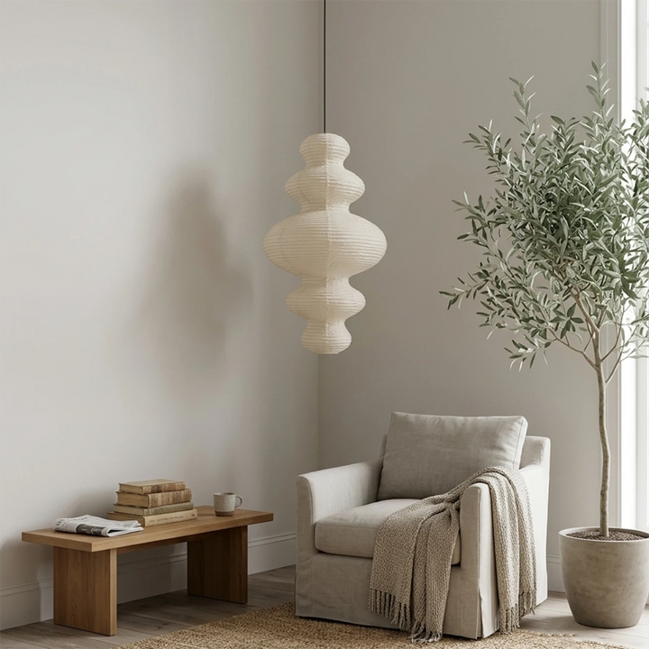 Sculptural paper pendant in a reading corner beside an olive tree