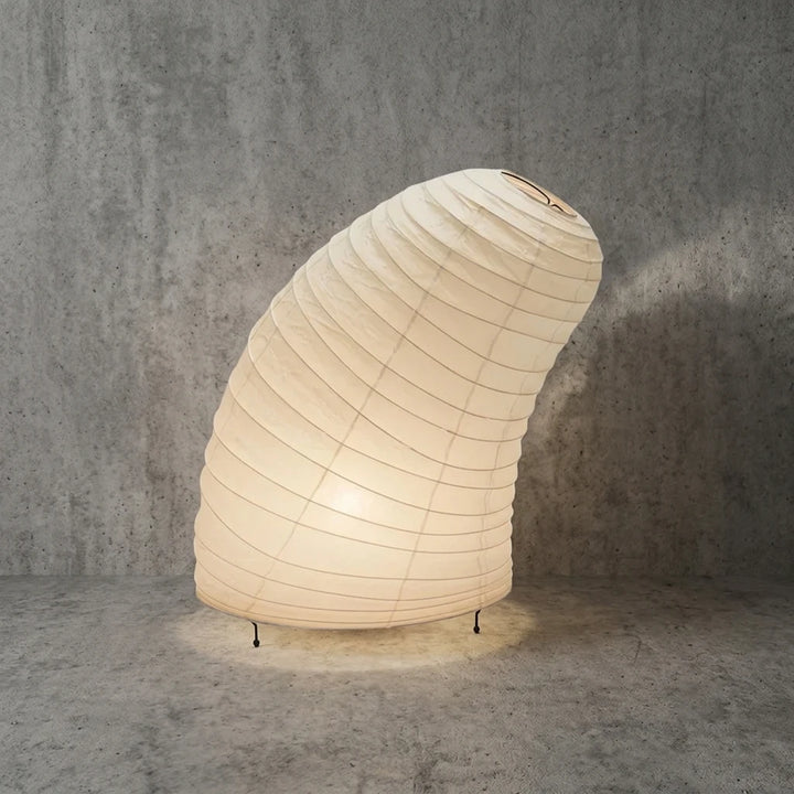 Full view of the shell-shaped paper table lamp on its slim metal legs