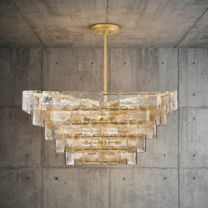 Smoked glass panel chandelier lit warmly against a raw concrete backdrop