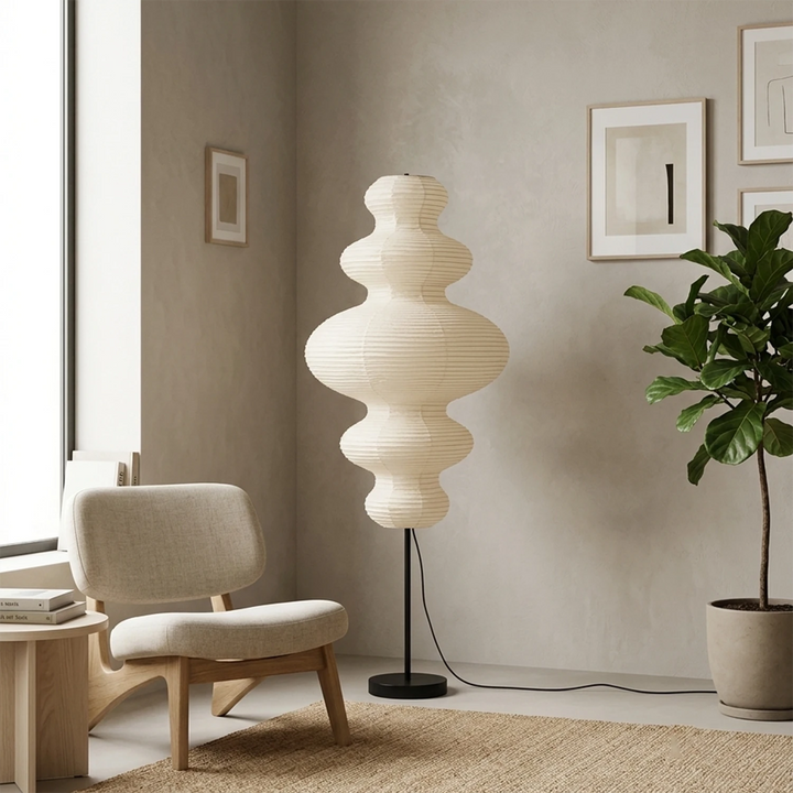 Stacked paper floor lamp beside a bouclé armchair in soft daylight