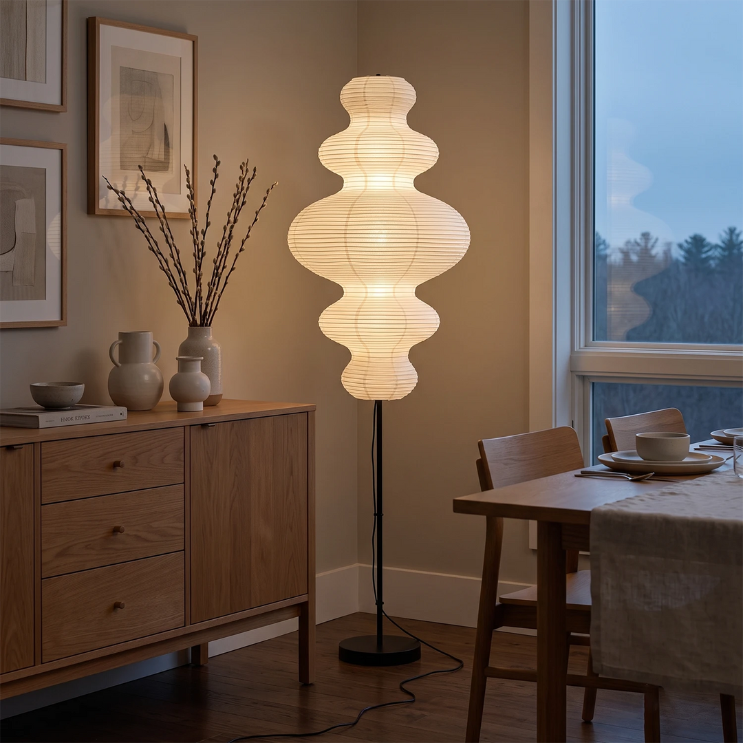 Stacked paper floor lamp in a dining corner beside a wooden sideboard