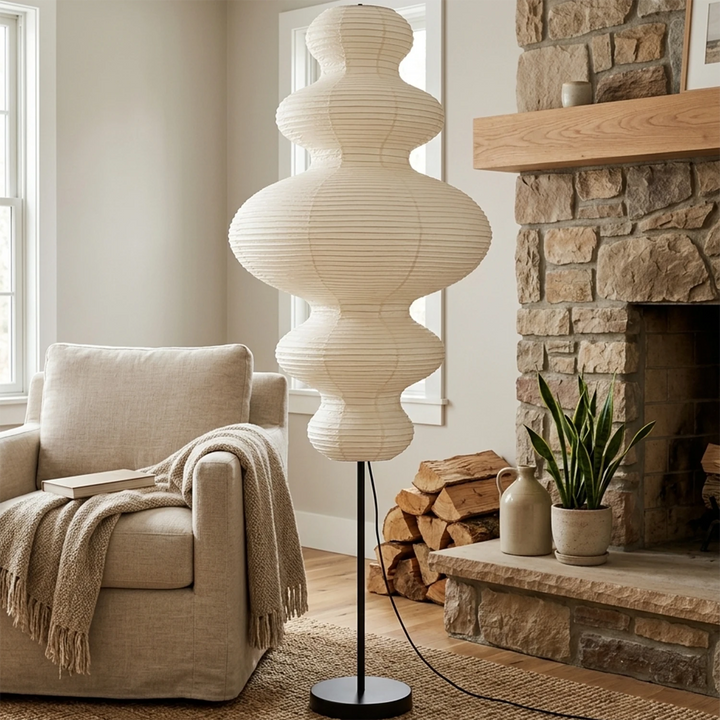 Stacked paper floor lamp beside a stone fireplace with a draped throw