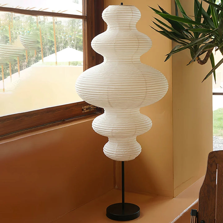 Stacked paper floor lamp beside a staircase in a warm plaster corner