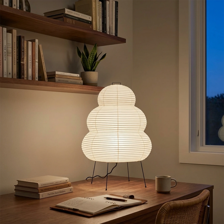 Stacked paper table lamp on a desk in a book-lined corner