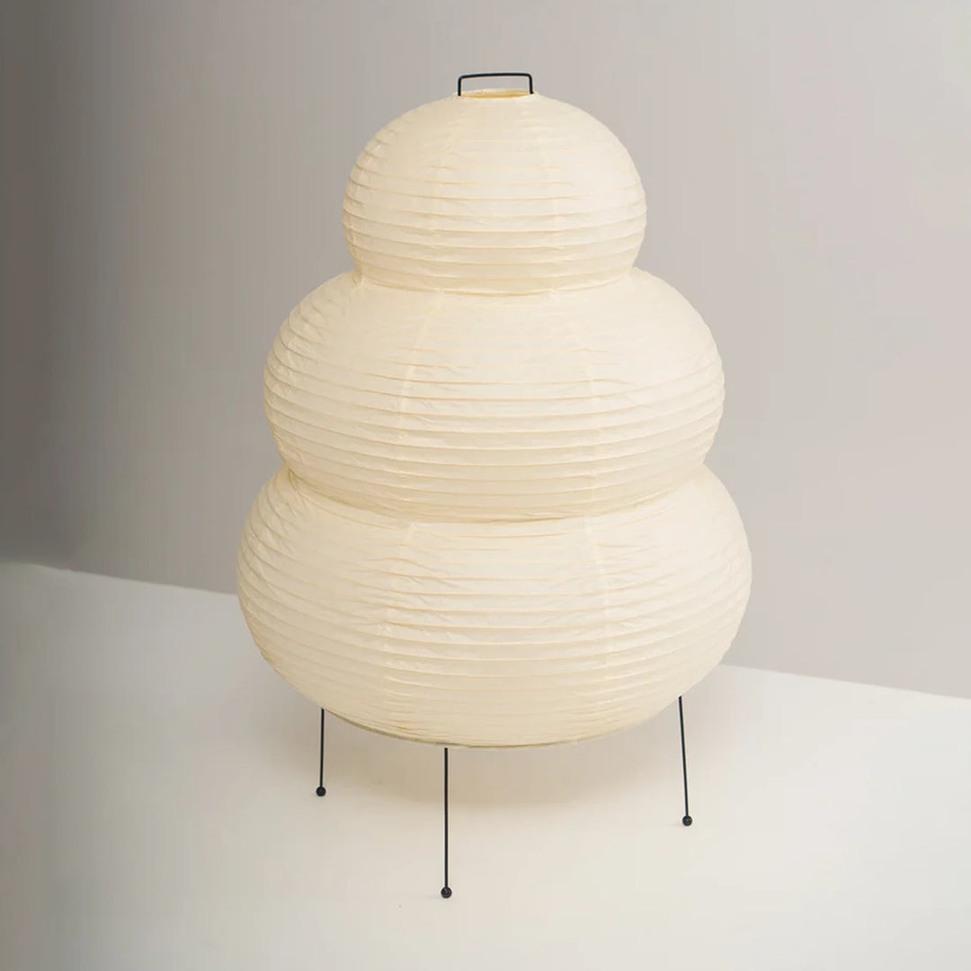 Full view of the stacked paper table lamp on its slim tripod legs
