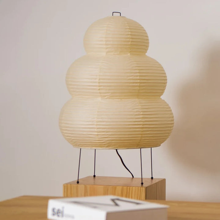 Stacked paper table lamp shown in side profile against a grey wall