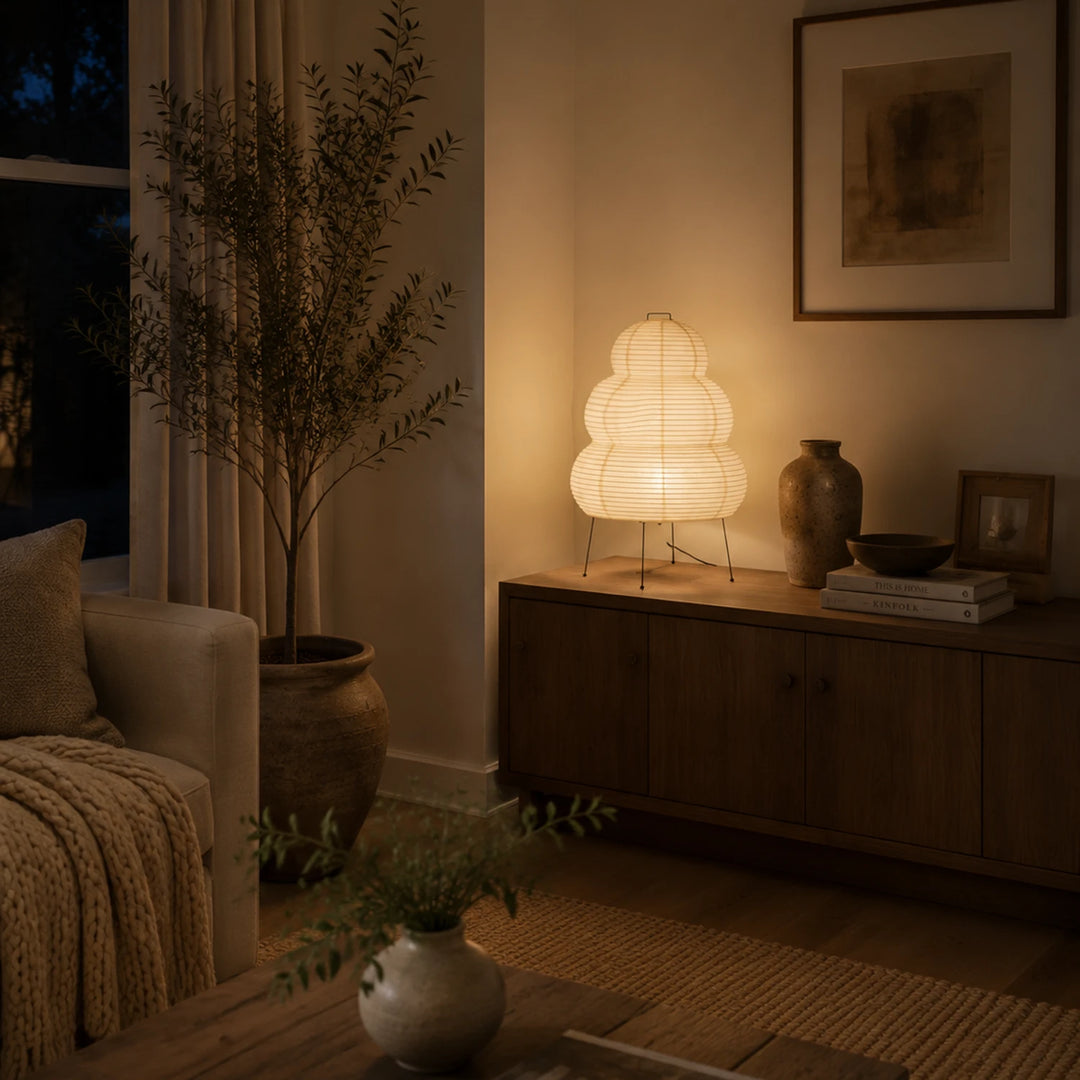 Stacked paper table lamp glowing warm on a sideboard in a bedroom corner