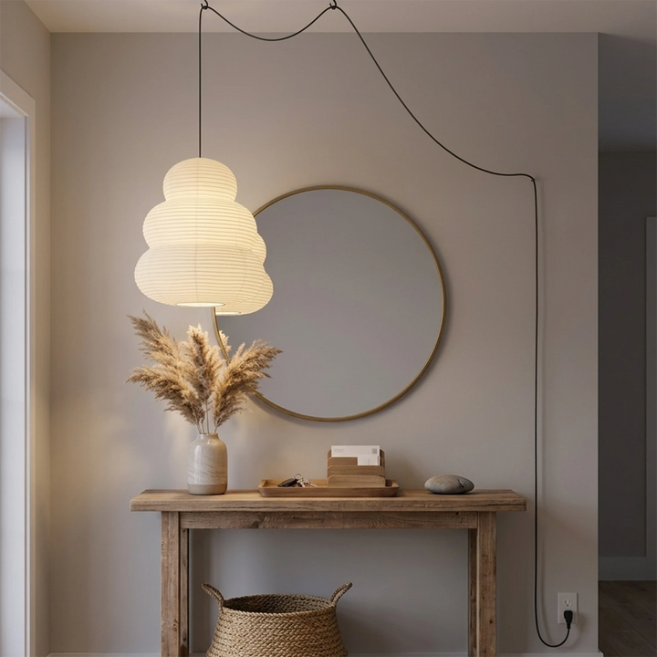 Stacked paper pendant above a console beneath a round mirror
