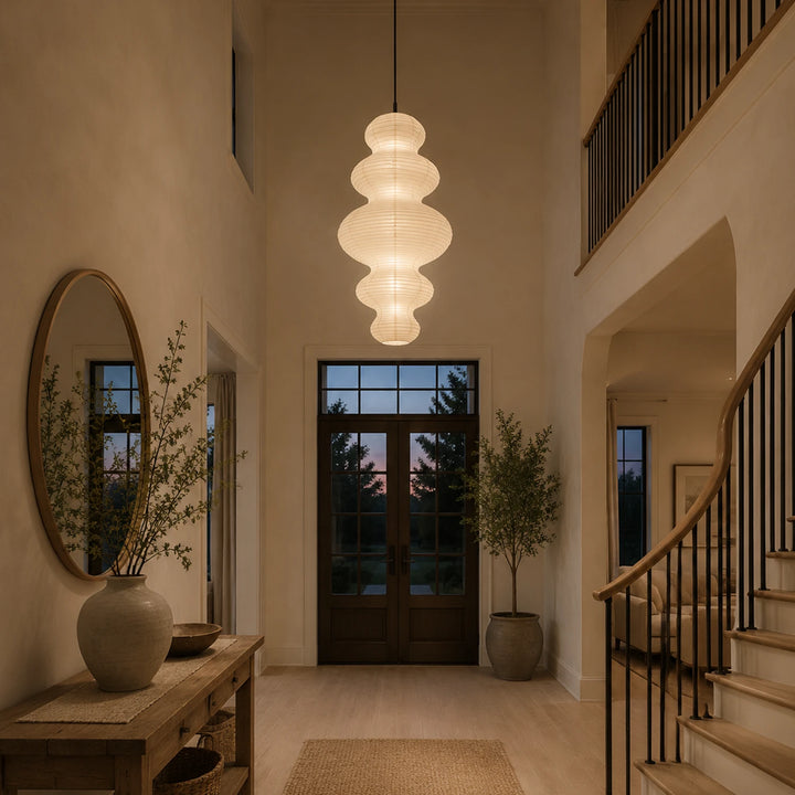 Stacked paper pendant in an entryway beside a round mirror and console