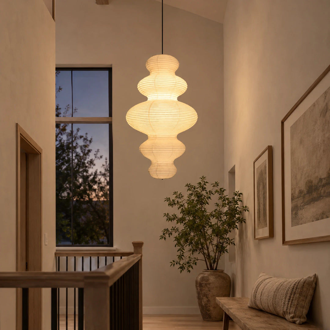 Stacked paper pendant glowing warm in a hallway corner with framed art