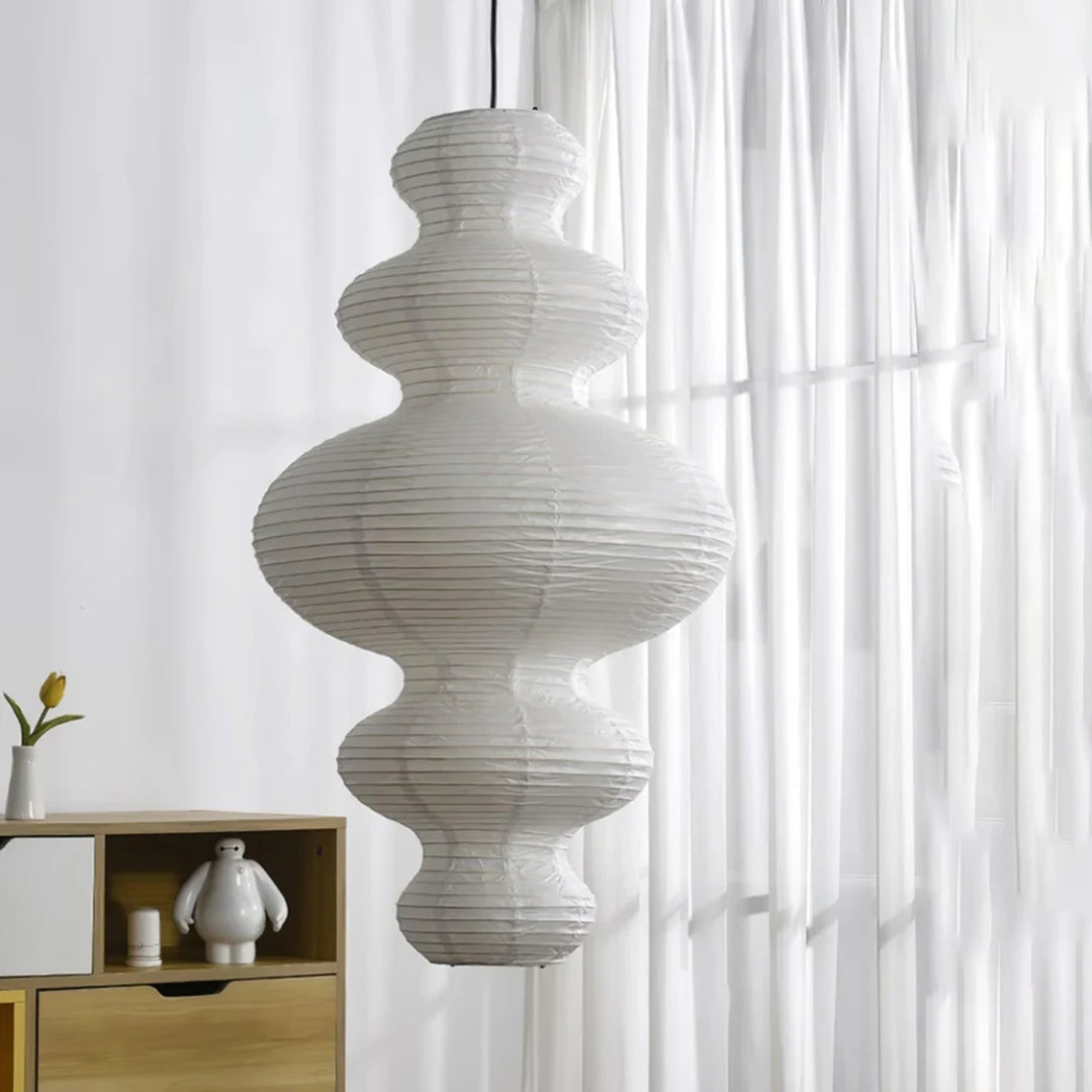 Stacked paper pendant glowing softly in front of sheer curtains