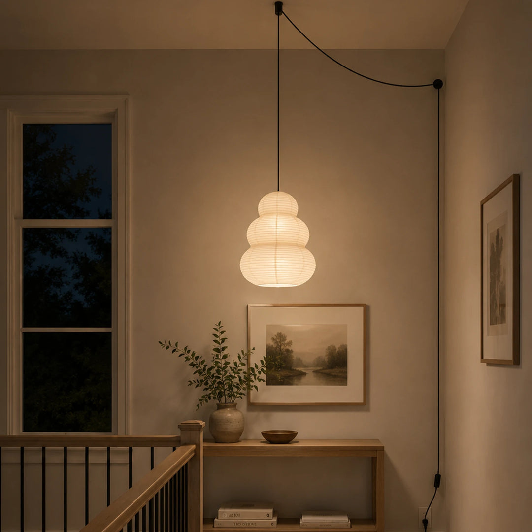Stacked paper pendant hanging over a stair landing with framed art