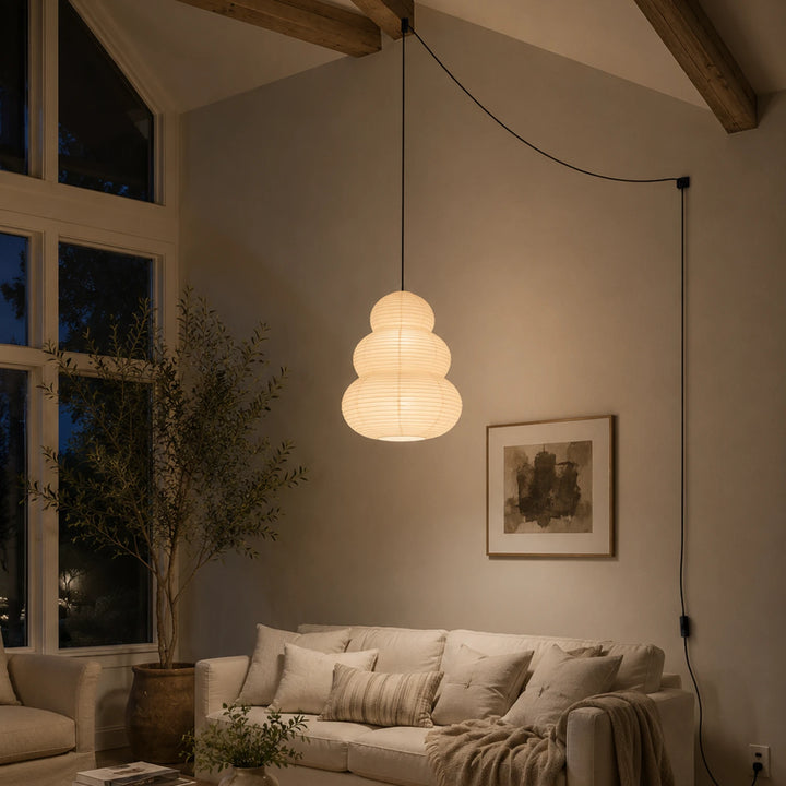 Stacked paper pendant in a vaulted living room beside tall windows