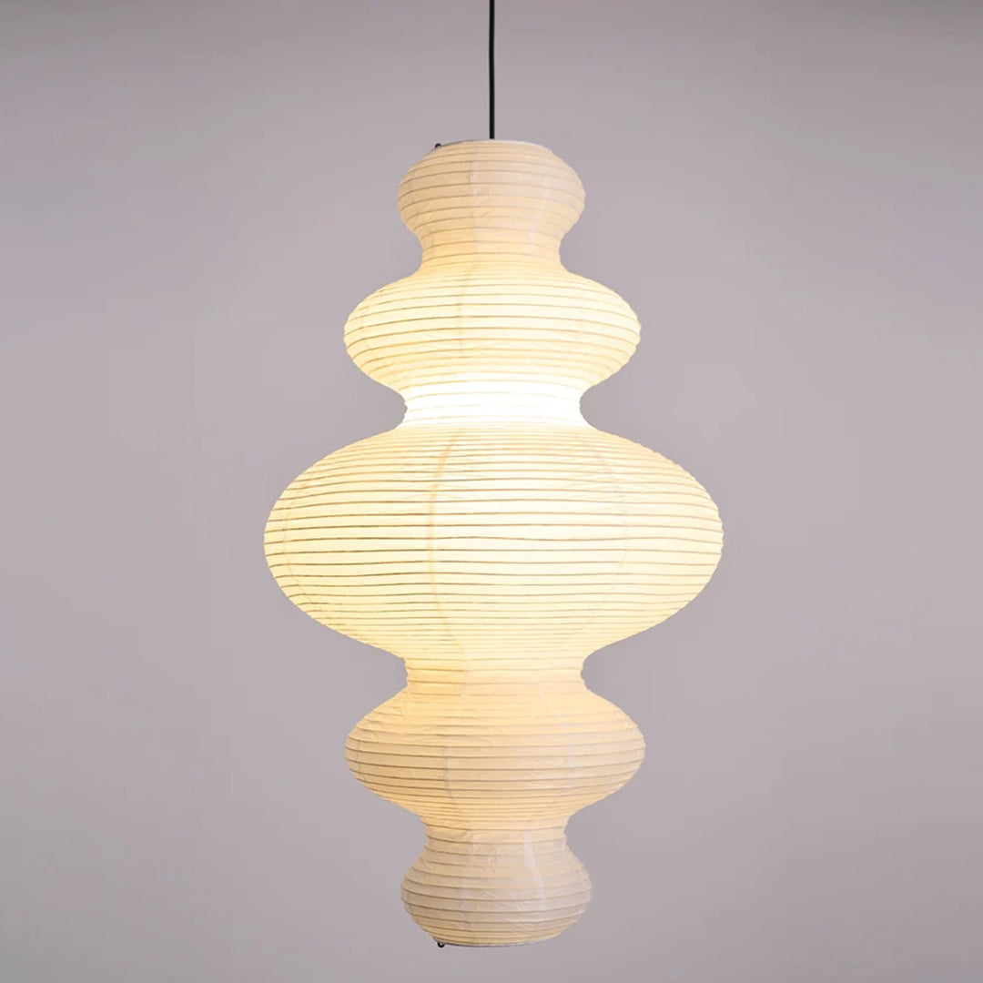 Stacked paper pendant glowing warm against a pale grey backdrop