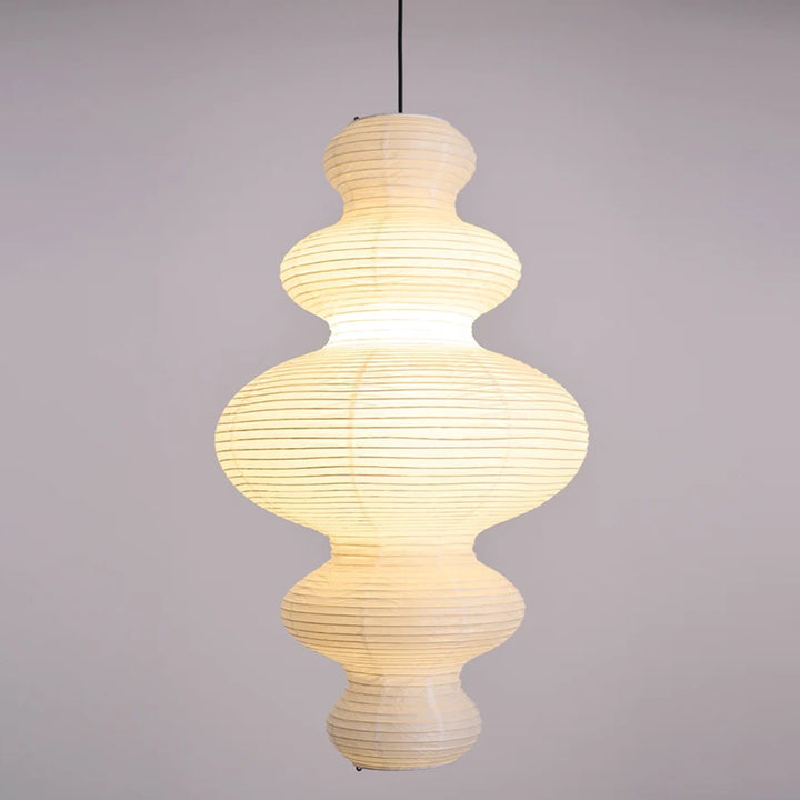 Stacked paper pendant glowing warm against a pale grey backdrop