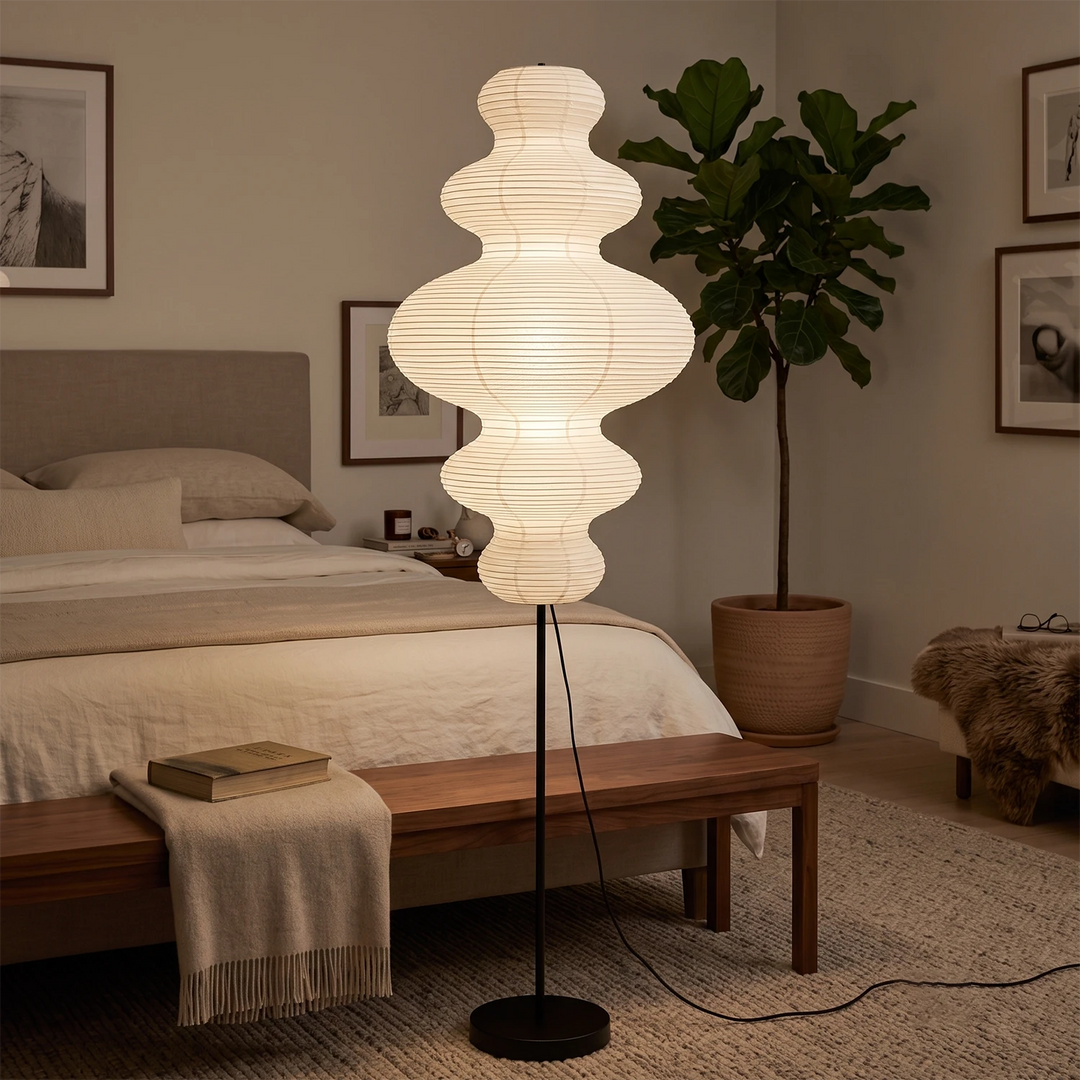 Tiered gourd paper floor lamp beside a bed with a wooden end bench