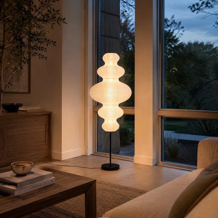 Tiered gourd paper floor lamp glowing beside a sofa in an evening room