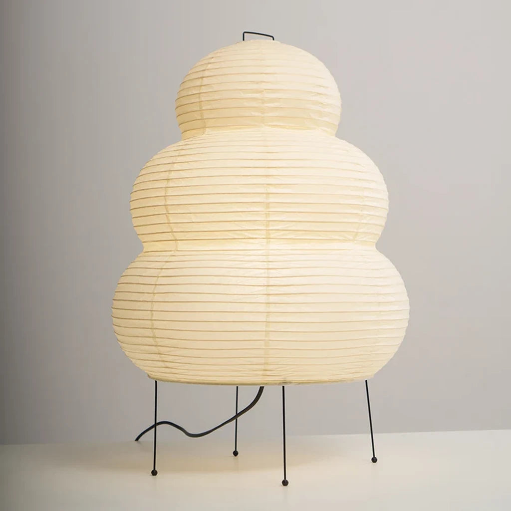 Tiered paper table lamp on a console beside dried stems and ceramics
