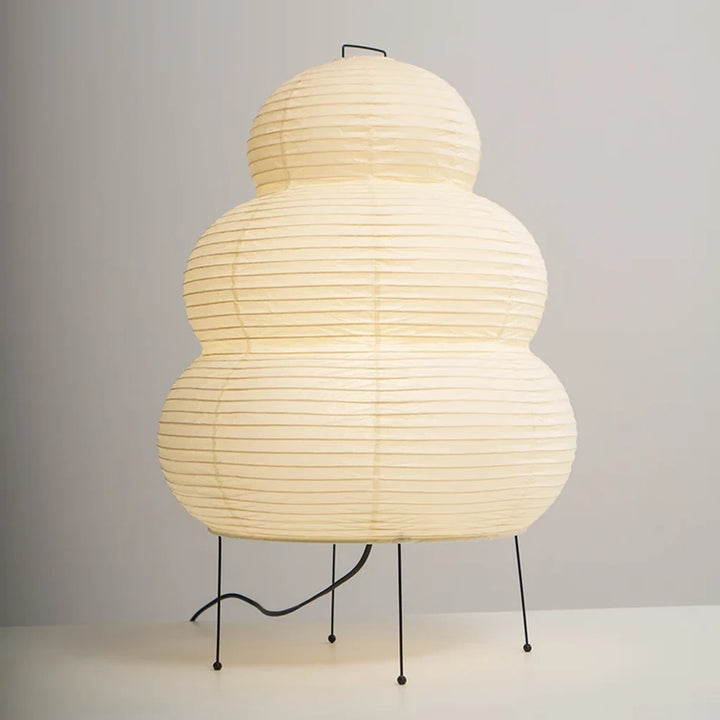 Tiered paper table lamp on a console beside dried stems and ceramics