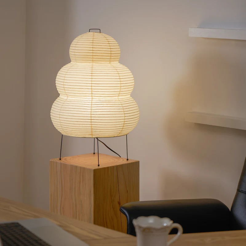 Tiered paper table lamp on a wooden console beneath a round mirror