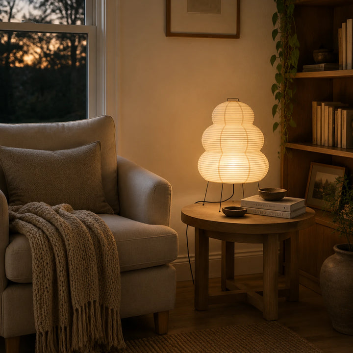 Tiered paper table lamp on a side table in a cozy reading corner at evening