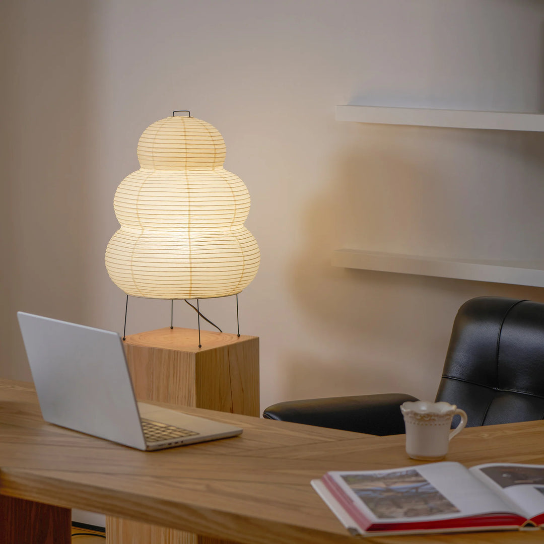 Tiered paper table lamp on a study desk backed by open shelving