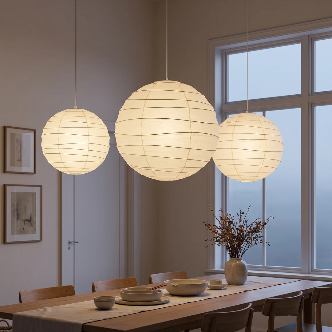Three paper pendants hanging in a row above a long wooden dining table