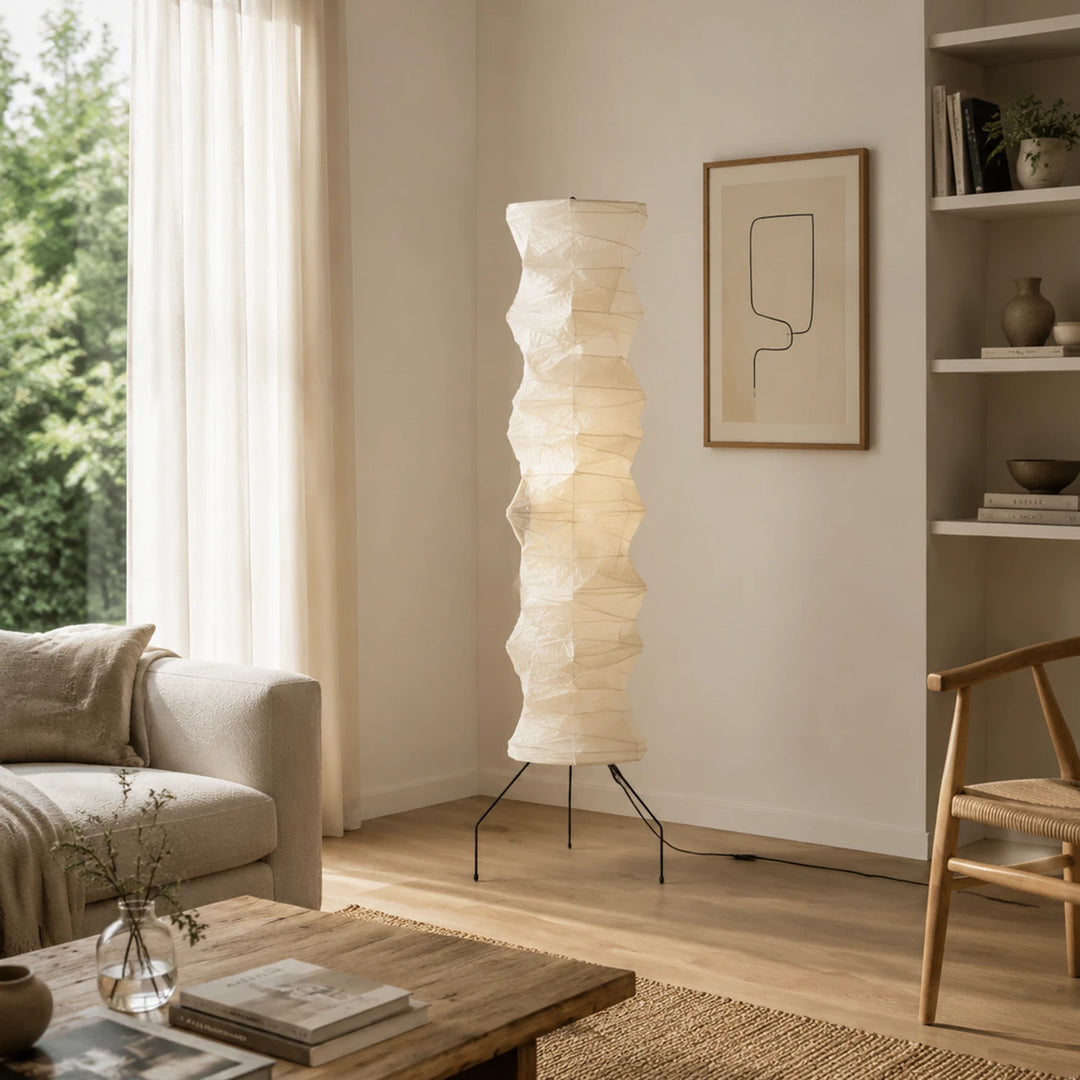 Tripod paper floor lamp in a daylit living room with shelving and artwork