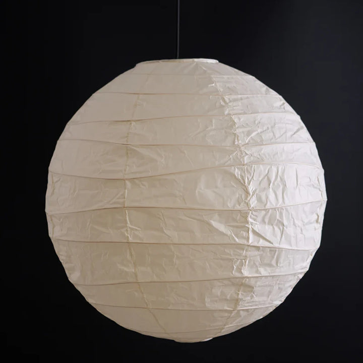 Unlit paper globe shade showing its natural off-white tone on a dark backdrop