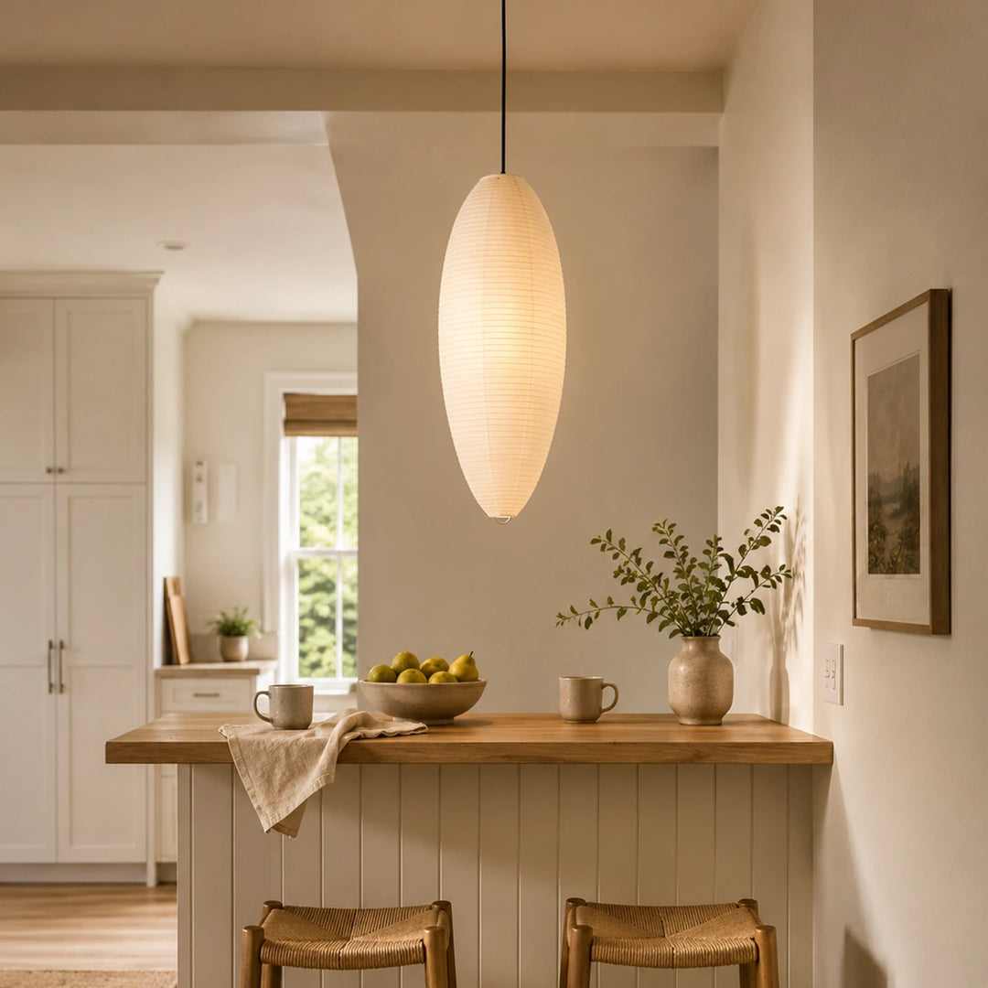 Oval paper pendant glowing warm in an evening corner with framed artwork