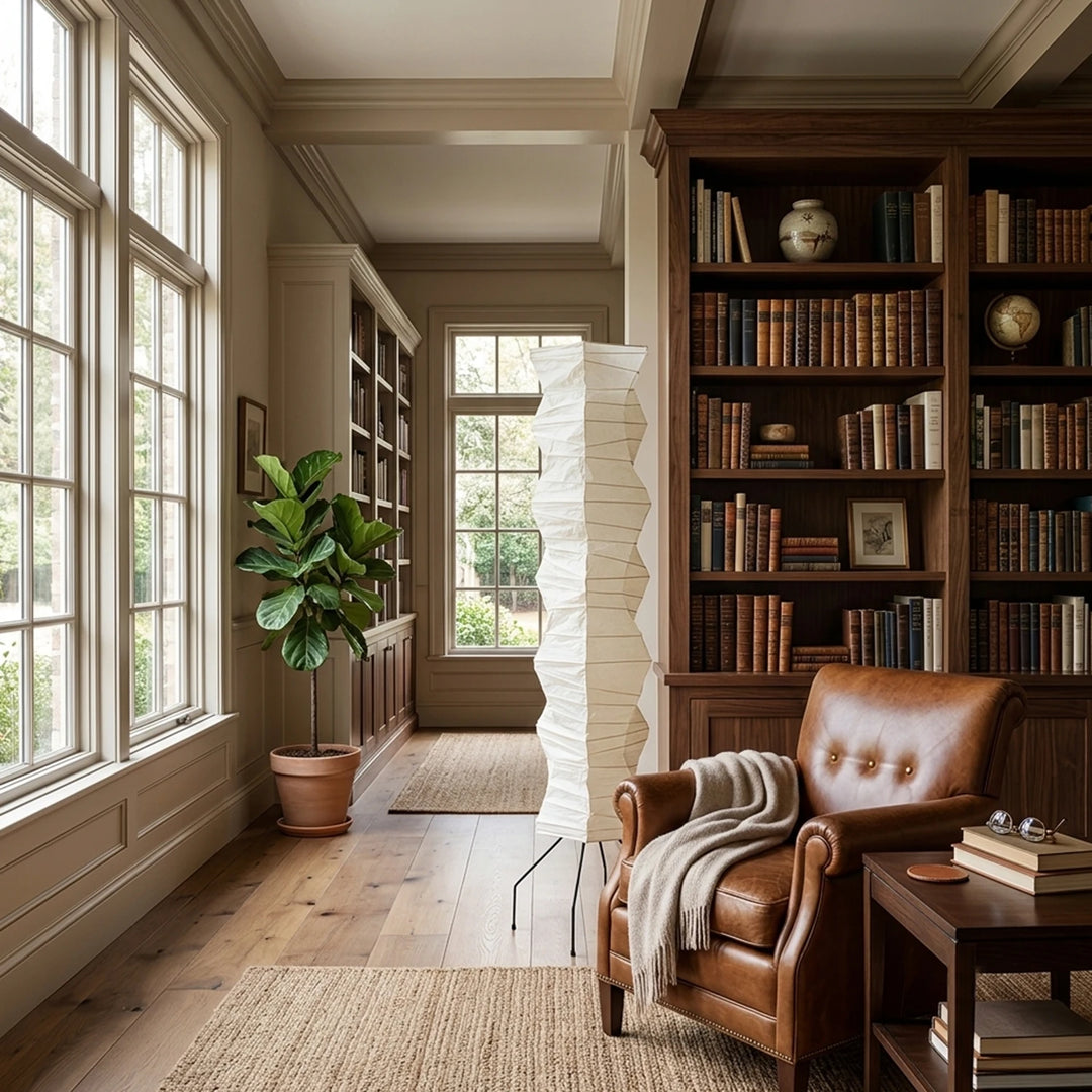 Paper floor lamp casting warm light in a home library with leather armchair