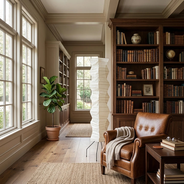 Paper floor lamp casting warm light in a home library with leather armchair