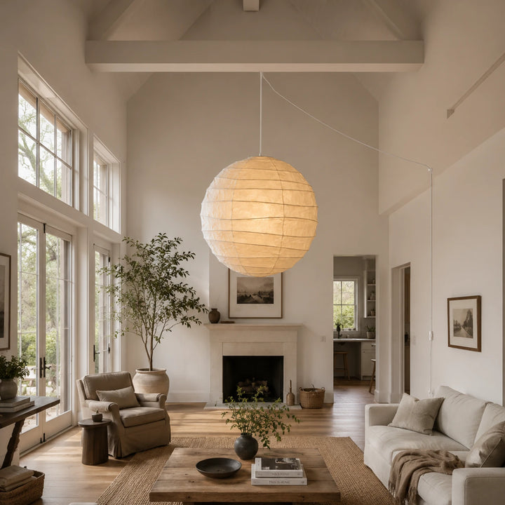Paper pendant glowing in a double-height living room with a stone fireplace
