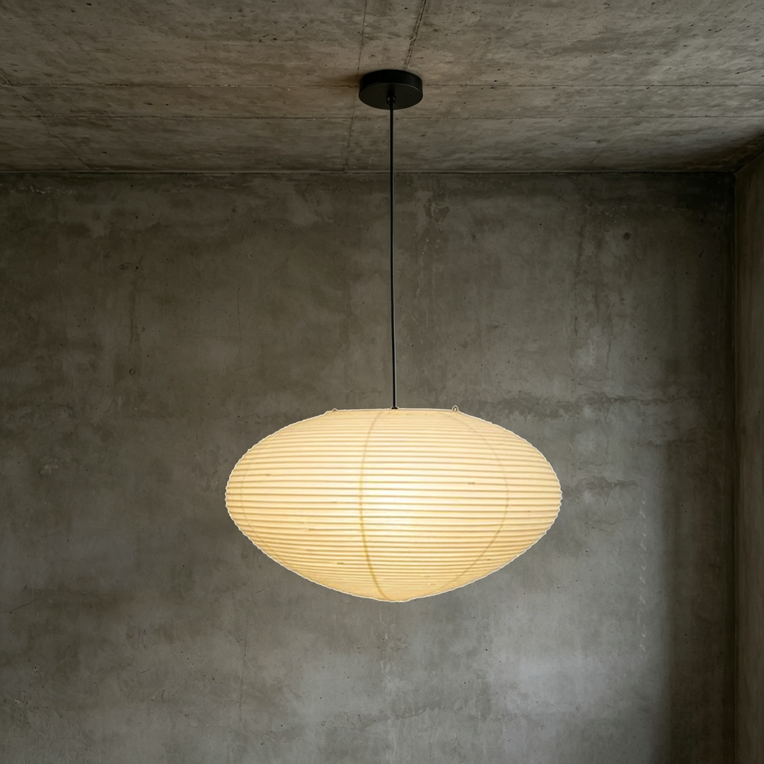 Washi paper oval pendant light with black suspension cord against raw concrete wall background