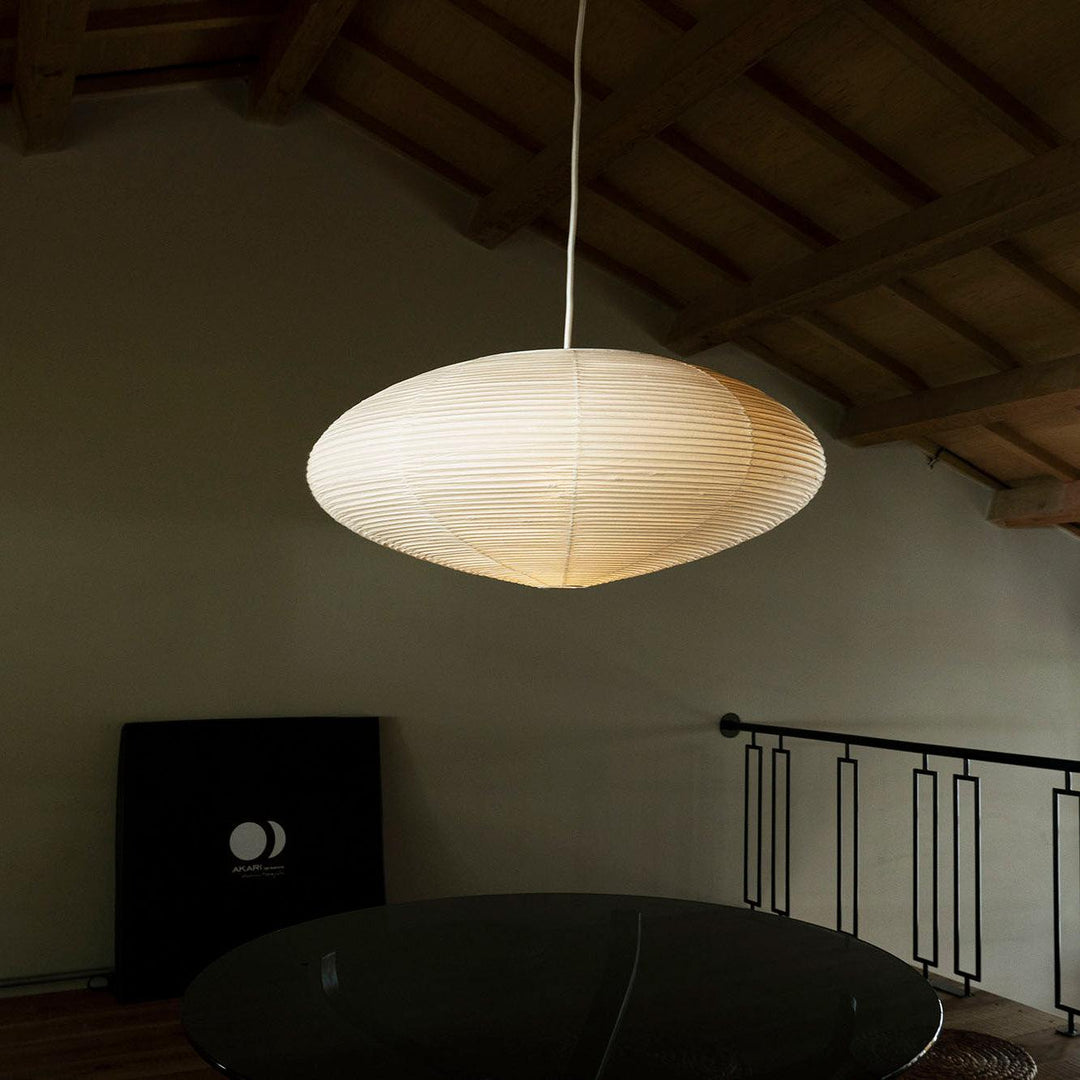 Glowing oval washi paper pendant under exposed wooden beam sloped loft ceiling