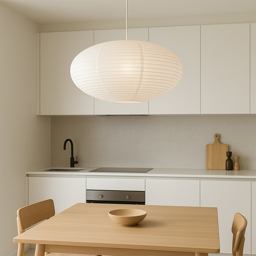 Oval washi paper pendant lamp above dining table adjacent to minimalist white modern kitchen