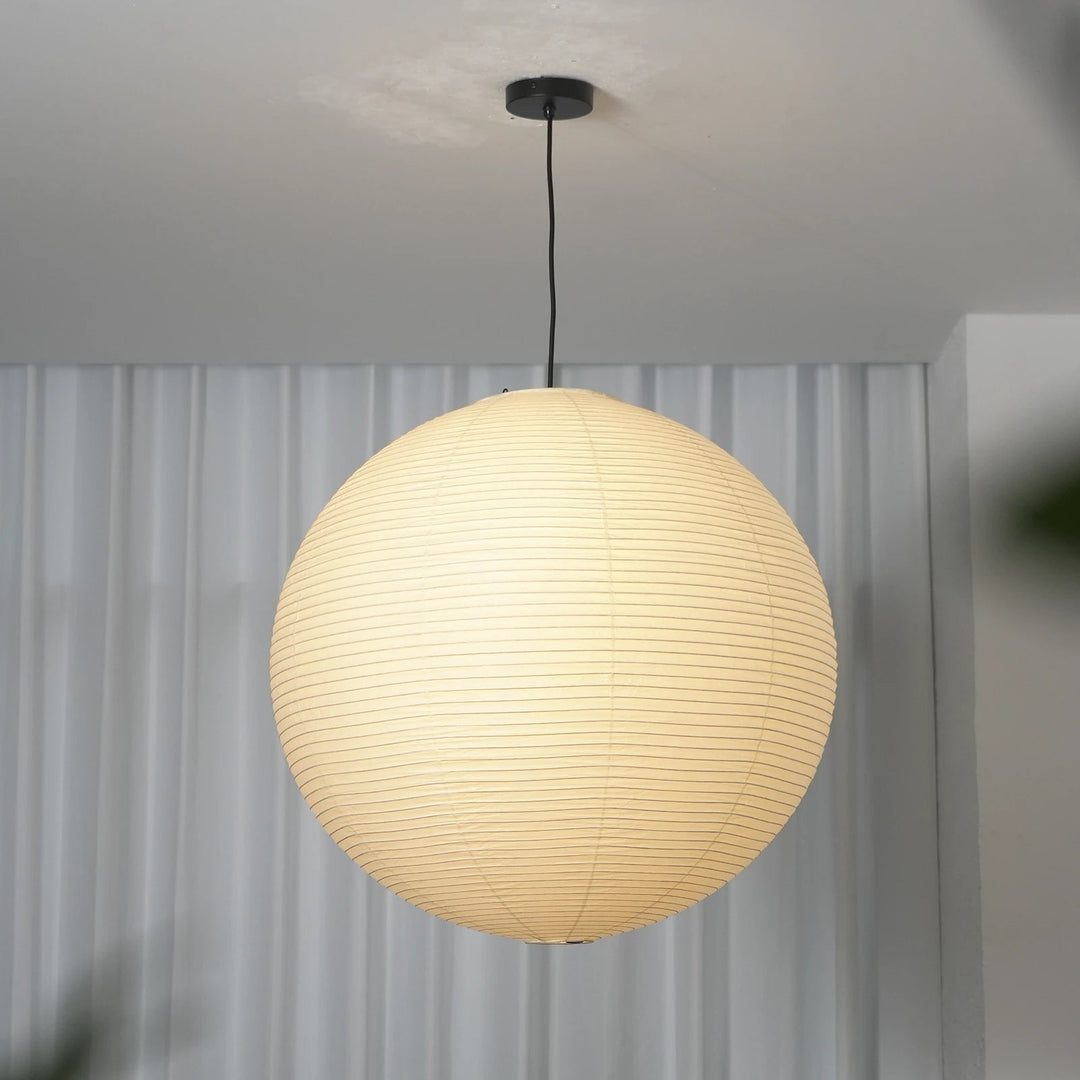 Full vertical shot of washi paper spherical pendant with black cord on light grey wall