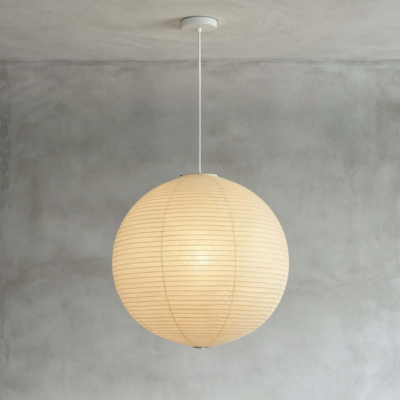 Spherical washi paper lamp with black hanging cord against matte grey interior wall